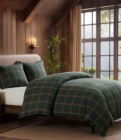 a bed in a bedroom next to a window with wood paneling on the walls