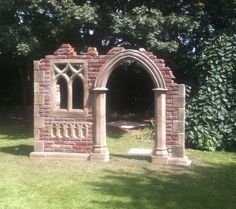 an arch in the middle of a grassy area