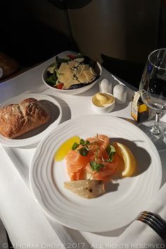 a white plate topped with food on top of a table next to a glass of wine