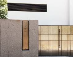 a metal object on the side of a building next to a wall with some tiles