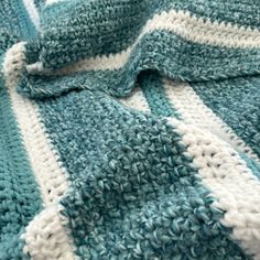 a blue and white crocheted blanket laying on top of a bed