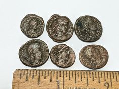 six ancient roman coins next to a ruler