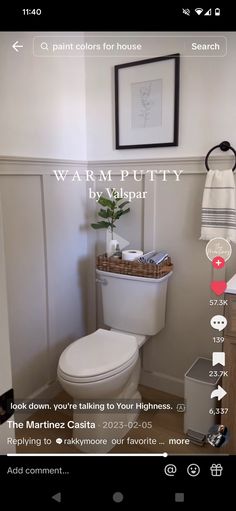 a white toilet sitting in a bathroom next to a wooden cabinet and framed pictures on the wall