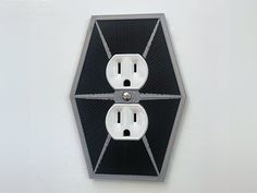 two black and white electrical outlets in the shape of a hexagonal object on a wall