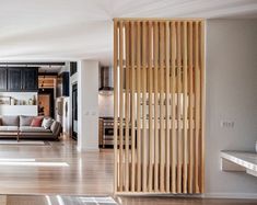 a living room filled with furniture and wooden slats on the wall next to a kitchen