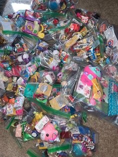 a pile of plastic toys on the floor next to a bag filled with them and other items