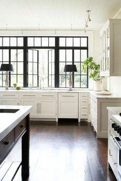 an image of a kitchen setting with white cabinets and dark wood flooring that says, if you're over those curtains go without windows