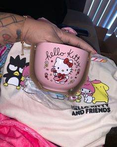 a hello kitty cup is being held up by someone's hand with tattoos on her arm