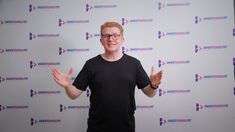 a man standing in front of a white backdrop with his hands out to the side