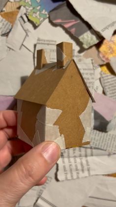 someone is holding a paper house in their hand