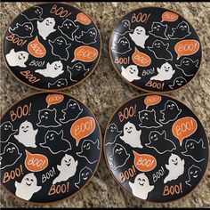 four halloween plates with ghost and boo on them sitting on a granite countertop in front of a marble wall