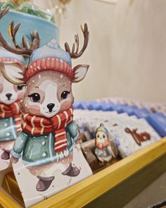 two deer figurines are on display in a wooden tray with other christmas decorations