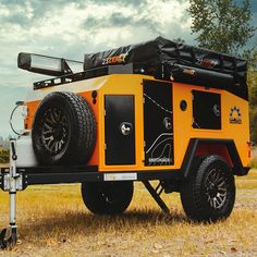 an orange and black utility vehicle parked in the middle of a field with trees behind it