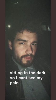 a man with a beard wearing a suit and looking at the camera while sitting in a car