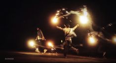 a group of people standing on top of a dirt field at night with their arms in the air