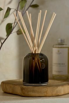 a black vase with sticks sticking out of it on a table next to a bottle