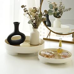 two white trays with vases and bottles on them sitting in front of a mirror