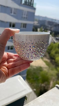 a hand holding a white cup with lots of small crystals on the outside and inside