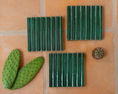 three pieces of green plastic sitting on top of a tile floor next to a cactus