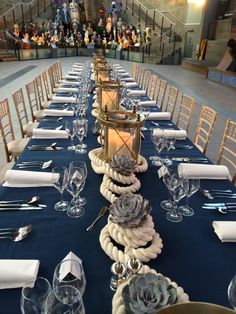 the table is set for an event with blue linens and white place settings, silverware