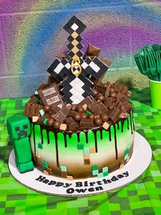 a birthday cake is decorated with chocolate and marshmallows on a green checkered tablecloth