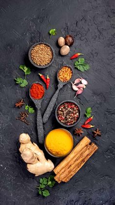 spices and herbs arranged in bowls on a dark background with space for text or image