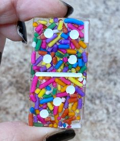 a person holding up a small plastic case filled with colorful sprinkles and buttons