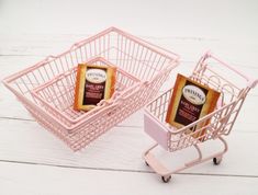 two pink shopping carts with tea bags in them sitting on a white wooden floor next to each other