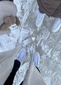 two people standing in the snow with one holding a teddy bear and looking up at them