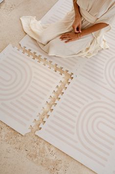 a woman sitting on the floor next to two pieces of white foam that have been cut out