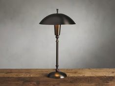 a lamp that is sitting on top of a wooden table in front of a gray wall