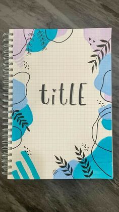 a spiral notebook with the word title written in black ink on top of a blue and pink floral pattern