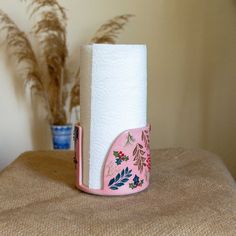 a roll of toilet paper sitting on top of a table next to a flower pot