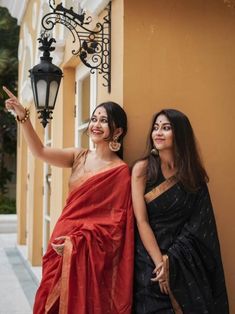 two women standing next to each other in front of a light pole and lamp post