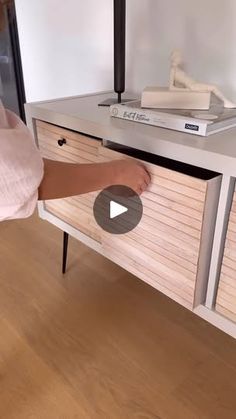 a person is opening the drawers on a dresser in a room with wood floors and white walls