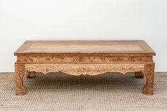 an old wooden table sitting on top of a carpeted floor next to a white wall