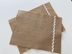 two pieces of burlocked linen with white stitching on each one side