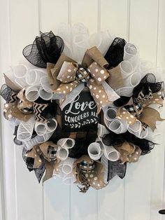 a wreath hanging on the front door with some burlocks and lace around it