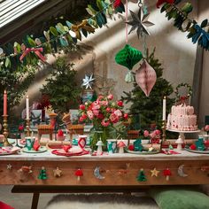 a table topped with lots of cakes and desserts covered in frosting next to christmas trees