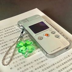 an electronic device is sitting on top of a piece of paper with a clover charm attached to it