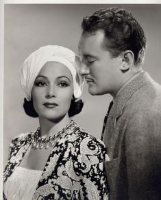 an old black and white photo of a man kissing a woman's forehead with a turban on her head