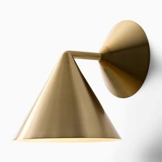 a gold wall light on a white wall next to a black and brown lamp shade