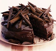 a chocolate cake with one slice cut out and the other half eaten, on a pink background