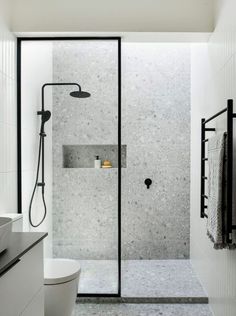 a bathroom with a walk in shower next to a white toilet and black accents on the walls