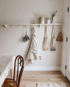 a room with white walls and wooden flooring, hanging hooks on the wall above a bed