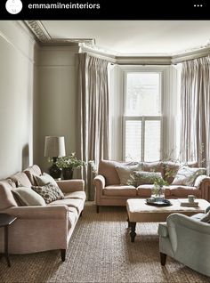 a living room with couches, chairs and tables in front of a large window