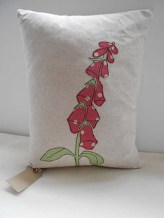 a white pillow with red flowers embroidered on the front and back, sitting on a table