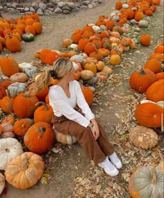 a woman sitting on top of a pile of pumpkins