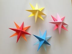 four different colored origami stars on a white surface