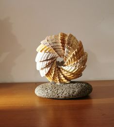 a rock sitting on top of a wooden table next to a small shell shaped sculpture